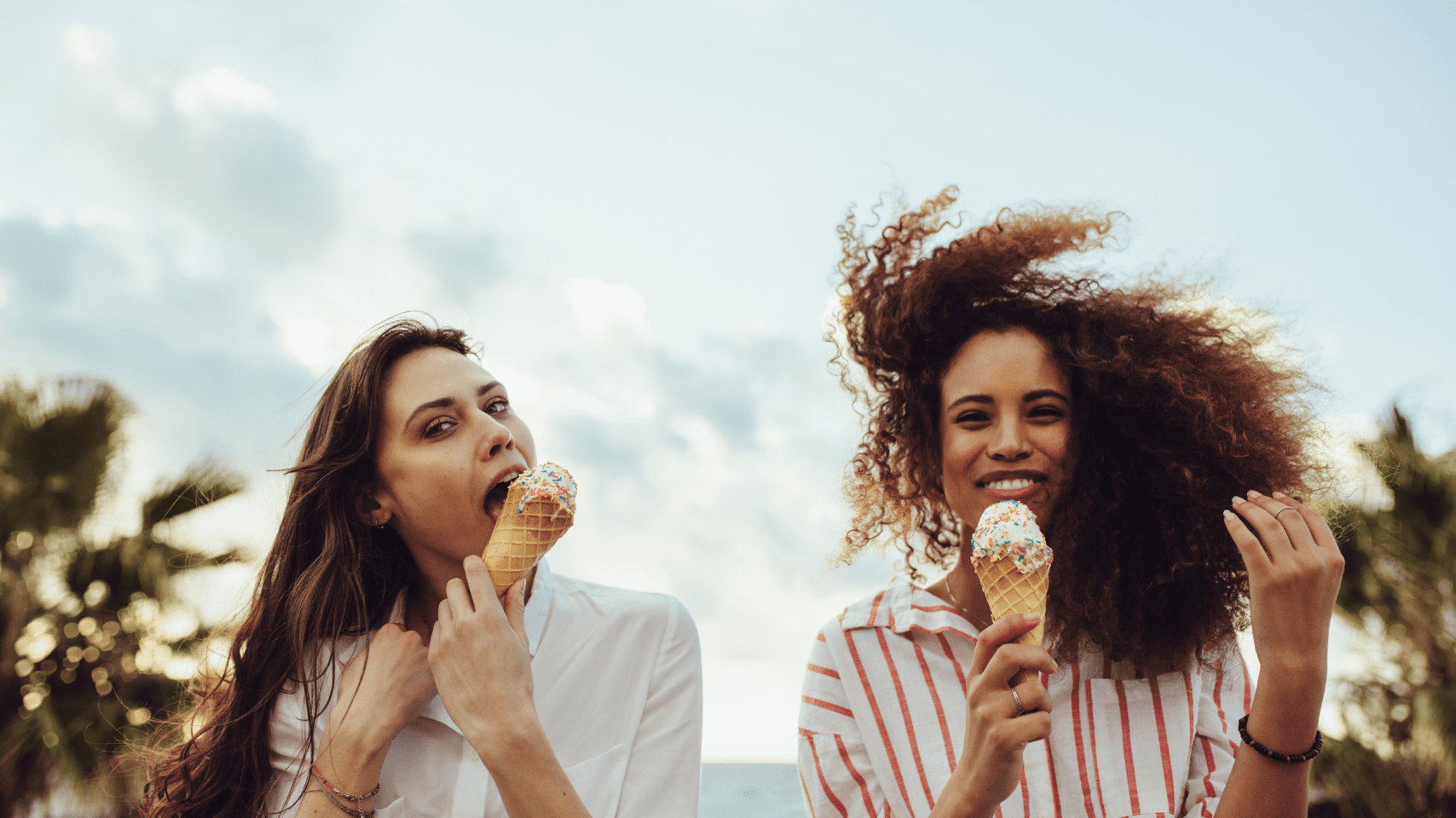 Two young women smiling and enjoying ice cream together outdoors, symbolizing freedom and positive experiences with food during eating disorder recovery.